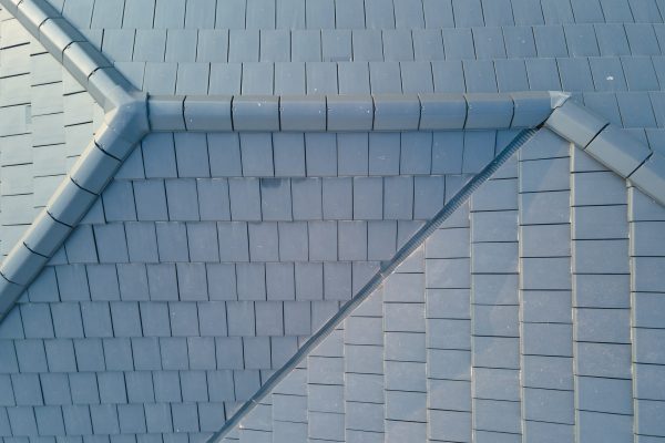 Closeup of house roof top covered with ceramic shingles. Tiled covering of building.