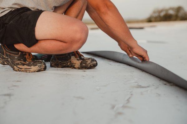 Worker applies pvc membrane roller on roof very carefully